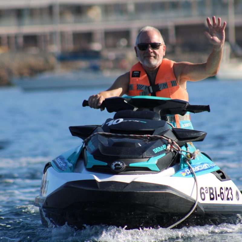 a man riding on the back of a boat in the water