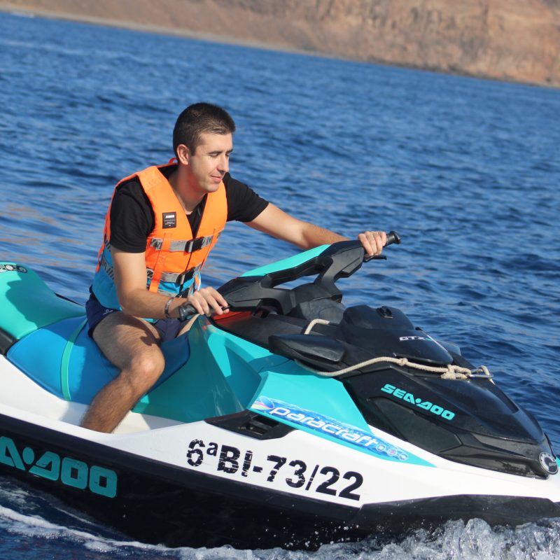a man riding on the back of a boat in the water